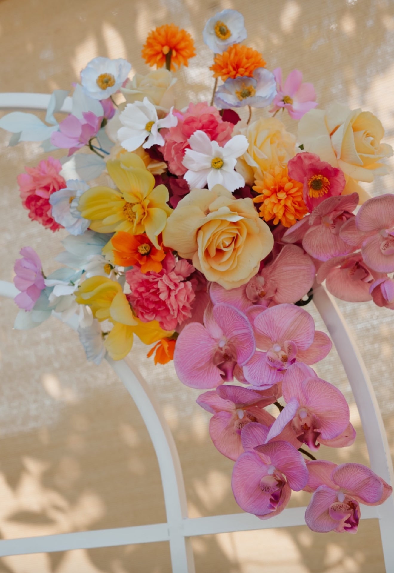 Colorful bouquet of flowers including pink, yellow, and orange on a white chair.