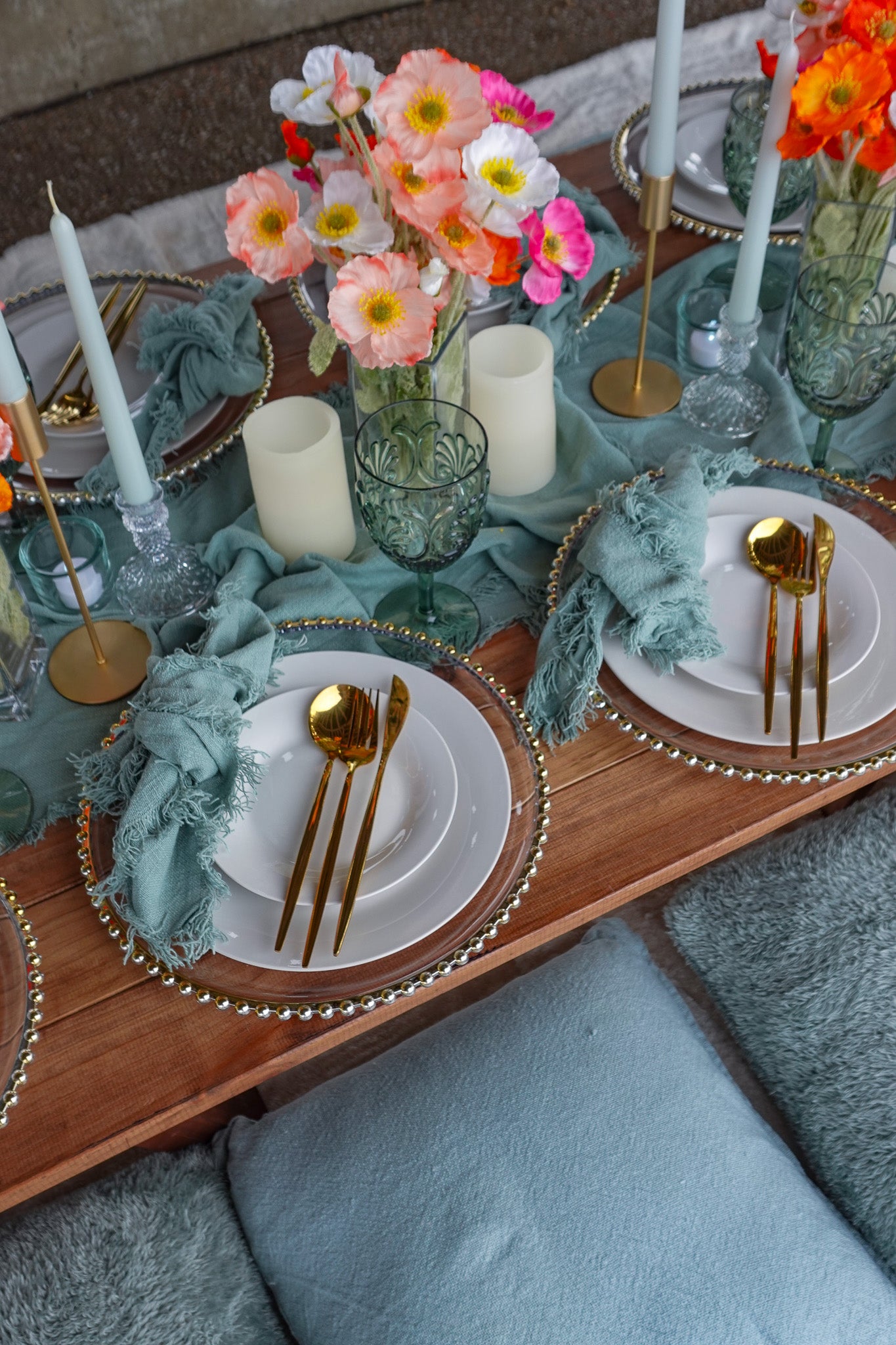 Luxury table scape set up with gold cutlery, blue glasses and pink and orange florals