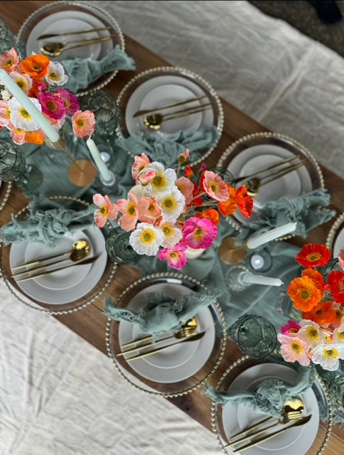 Blue green table set up with colourful flowers and gold cutlery