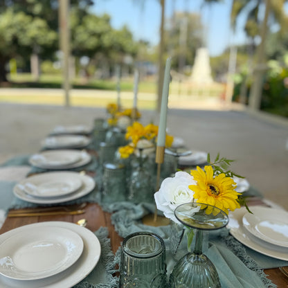Dining table set with plates, glasses, and floral decorations outdoors.