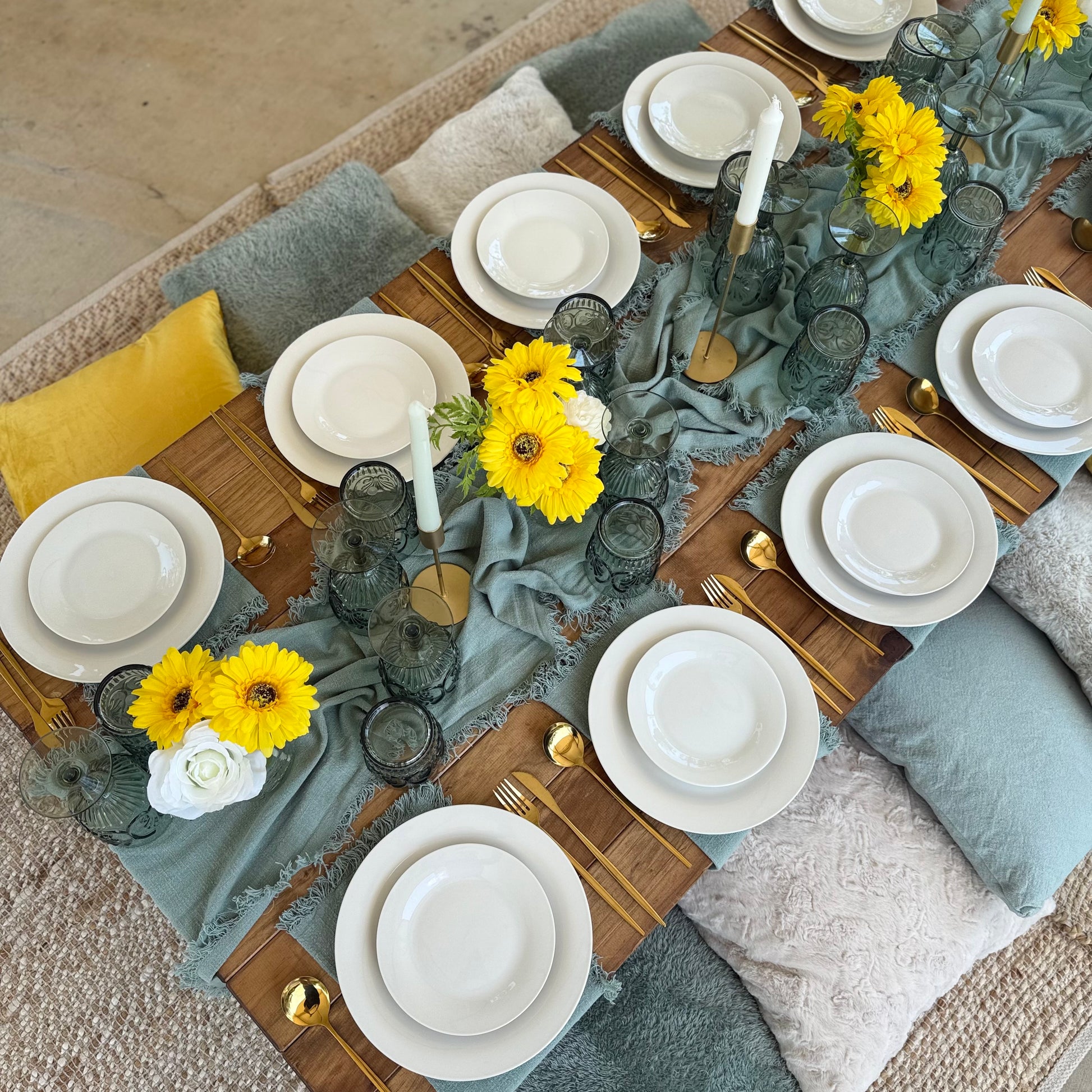 Elegant table setting with yellow flowers, gray tablecloth, and white plates.