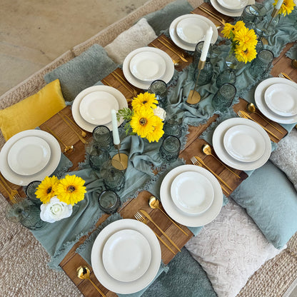 Elegant table setting with yellow flowers, gray tablecloth, and white plates.