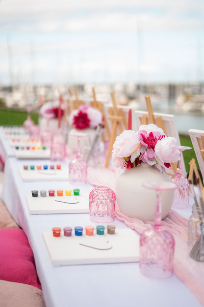 Decorative table setup with floral arrangements and colorful items on a blurred outdoor background