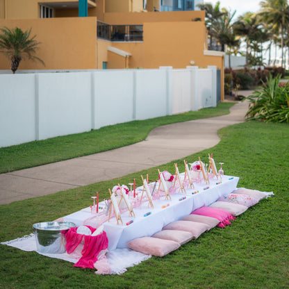 Outdoor setup with pink and white decorations on a grassy area near a building.